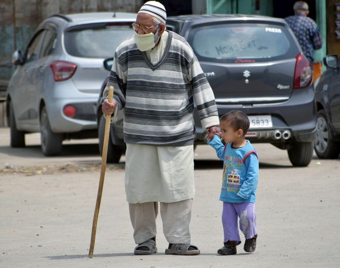 An elderly man walks with a kid outside Kheer Bhawani temple on the occasion of Kheer Bhawani Mela in Ganderbal on Saturday. (ANI Photo)